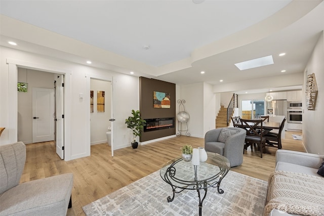 living room with stairway, baseboards, light wood finished floors, recessed lighting, and a glass covered fireplace