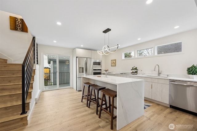 kitchen with a sink, modern cabinets, appliances with stainless steel finishes, and an island with sink