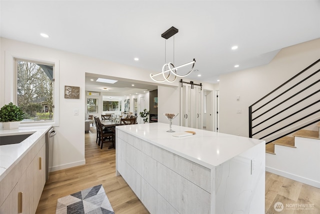 kitchen featuring a barn door, modern cabinets, light wood finished floors, and a center island