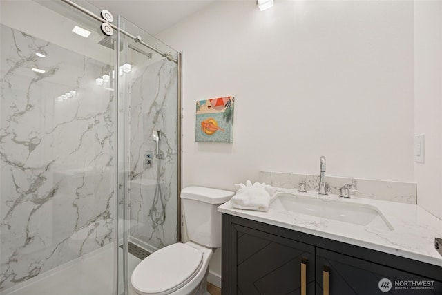 full bathroom featuring vanity, toilet, and a marble finish shower