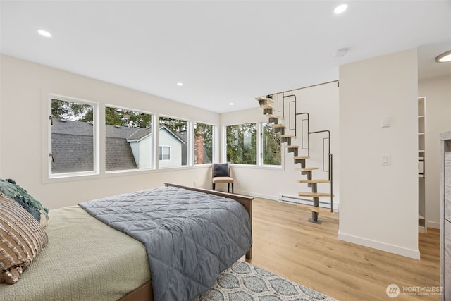 bedroom with a baseboard heating unit, recessed lighting, light wood-style floors, and baseboards