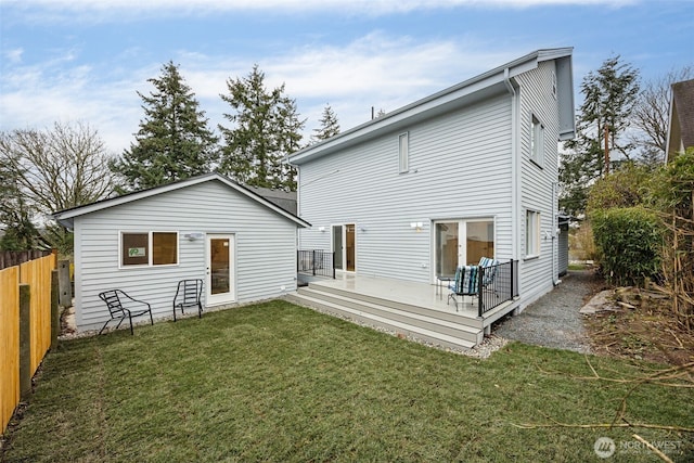 back of property featuring a deck, a yard, and fence