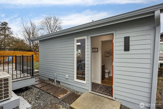 doorway to property featuring fence and a wooden deck