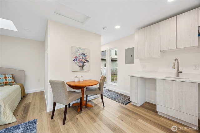 dining room featuring electric panel, baseboards, and light wood-style floors