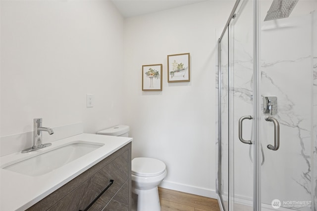 full bath featuring vanity, wood finished floors, baseboards, a marble finish shower, and toilet