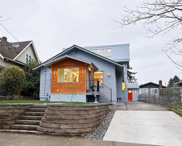 view of front facade with concrete driveway and fence