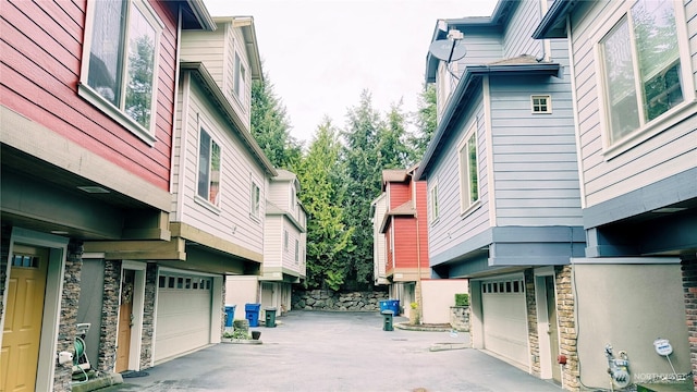 view of side of property featuring a garage, stone siding, and driveway