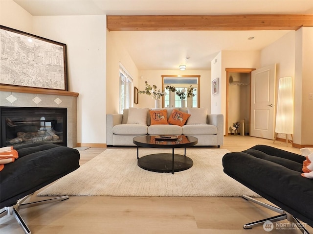 living room with baseboards, beam ceiling, wood finished floors, and a fireplace