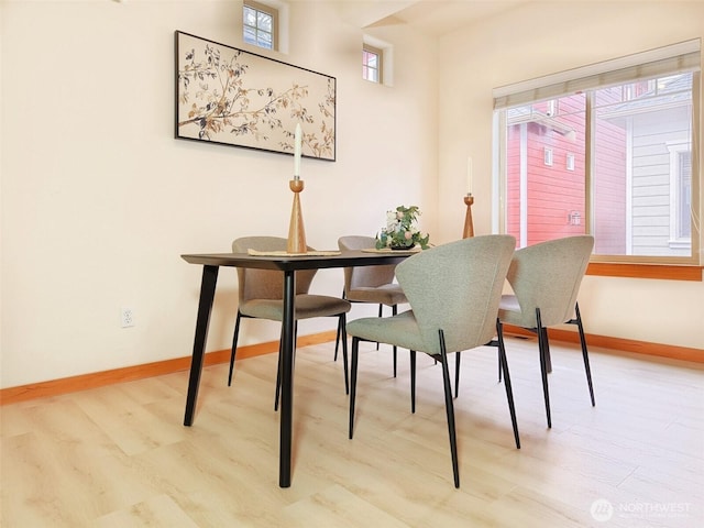 dining space featuring light wood-style flooring and baseboards