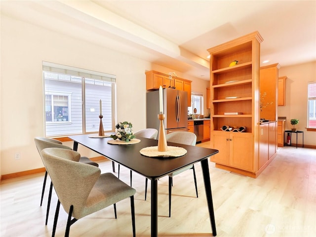 dining area with baseboards and light wood-style flooring