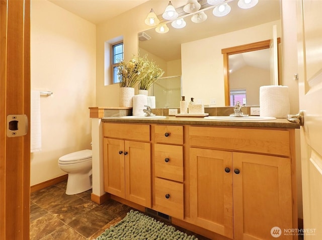 full bath with a sink, toilet, a stall shower, and double vanity