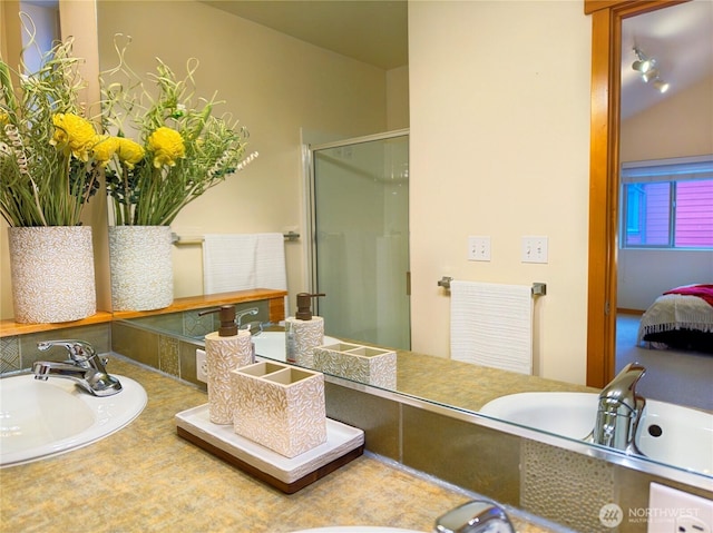 ensuite bathroom with double vanity, a stall shower, ensuite bathroom, and a sink