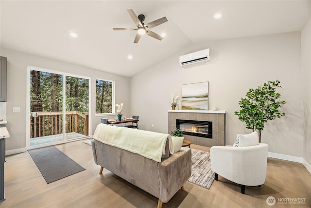 living area featuring an AC wall unit, a fireplace, light wood finished floors, baseboards, and vaulted ceiling