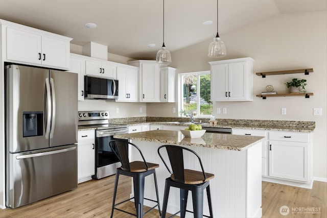 kitchen with a center island, appliances with stainless steel finishes, a breakfast bar area, white cabinets, and light wood finished floors