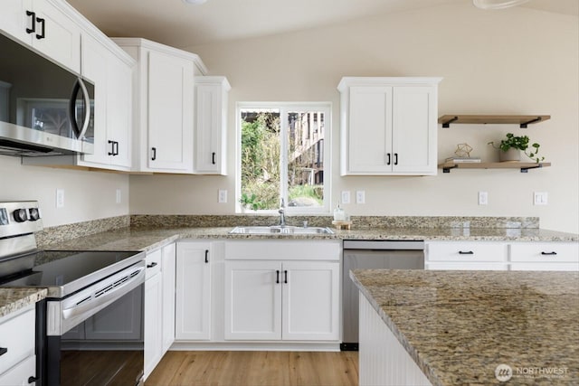 kitchen with light stone countertops, lofted ceiling, stainless steel appliances, white cabinetry, and a sink