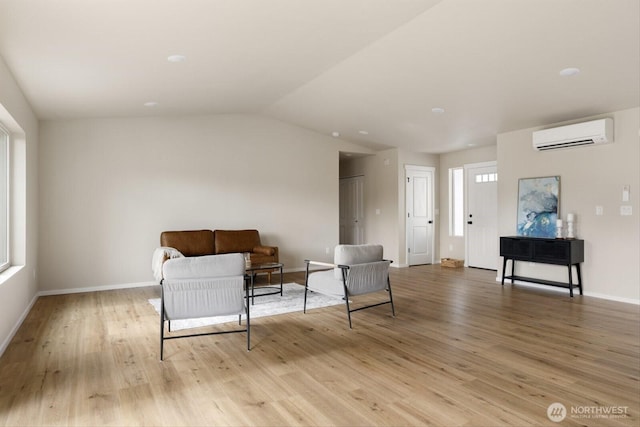 living area with lofted ceiling, light wood-style floors, baseboards, and a wall mounted AC