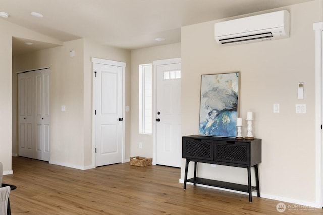 entryway with an AC wall unit, baseboards, and wood finished floors