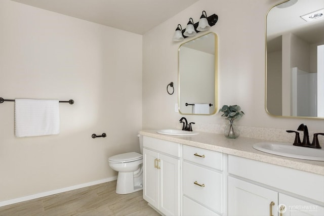 full bath with double vanity, toilet, wood finished floors, and a sink