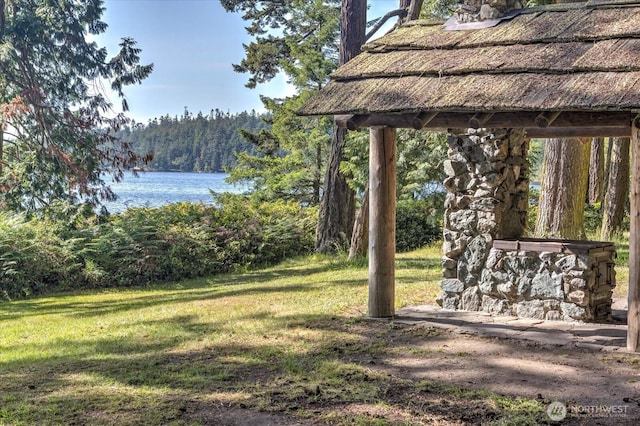 view of yard featuring a forest view and a water view