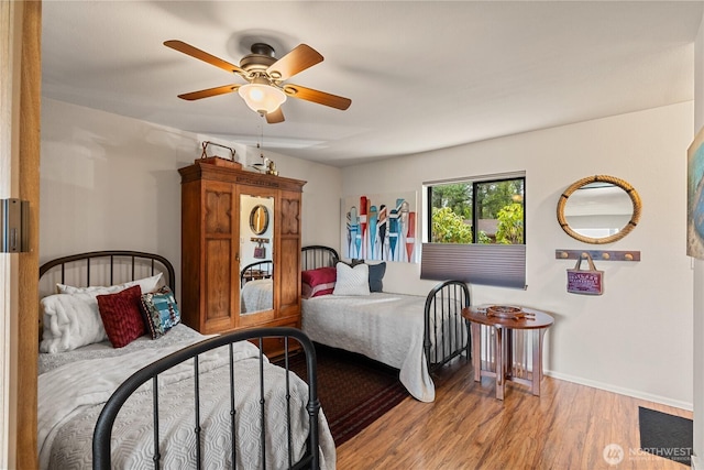 bedroom with baseboards, wood finished floors, and a ceiling fan