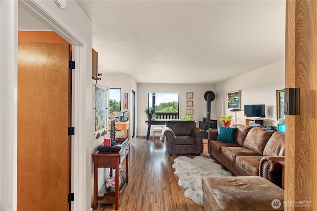 living room with a wood stove, wood finished floors, and baseboards