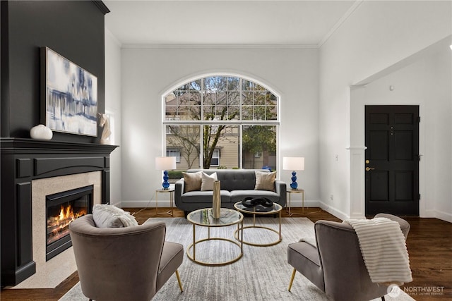 living room featuring ornamental molding, a tile fireplace, baseboards, and wood finished floors