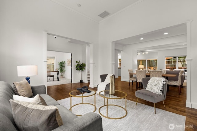 living area featuring visible vents, wood finished floors, baseboards, and ornamental molding