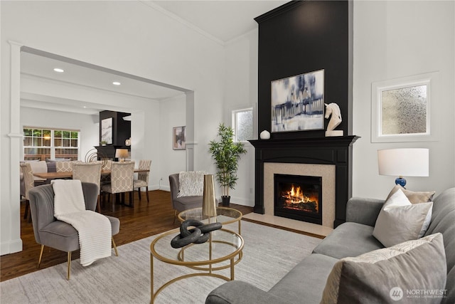 living room featuring crown molding, baseboards, a fireplace with flush hearth, recessed lighting, and wood finished floors