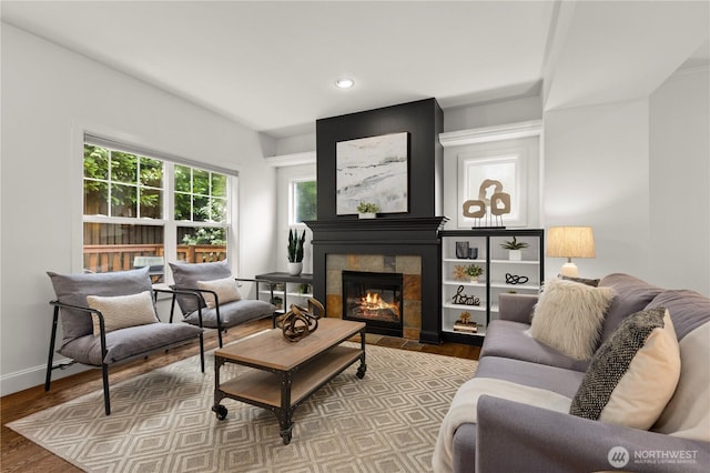 living room featuring recessed lighting, wood finished floors, baseboards, and a tile fireplace