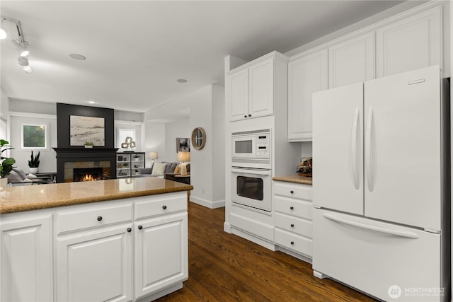 kitchen with white appliances, white cabinetry, a lit fireplace, and dark wood-style flooring