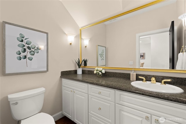 bathroom featuring vanity, lofted ceiling, and toilet