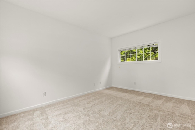 unfurnished room featuring light carpet and baseboards