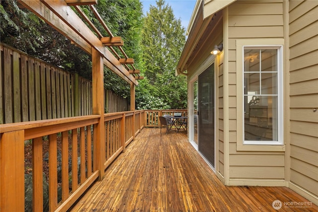 wooden terrace featuring outdoor dining space, a pergola, and fence