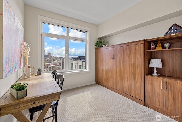 office with baseboards, light colored carpet, and a city view