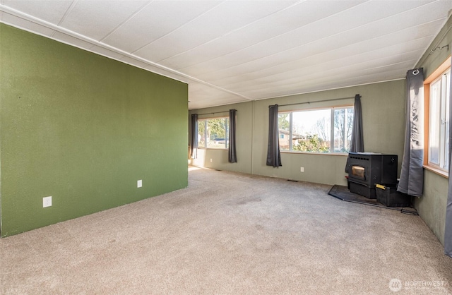 unfurnished living room with a wood stove, visible vents, and carpet floors