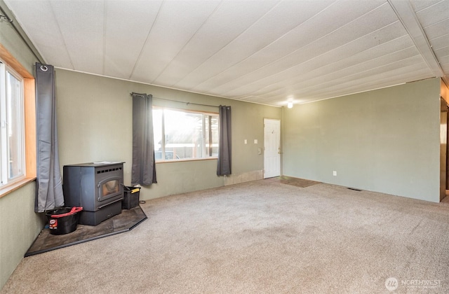 unfurnished living room featuring a wood stove and carpet flooring