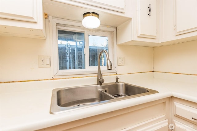 kitchen with white cabinetry, light countertops, and a sink