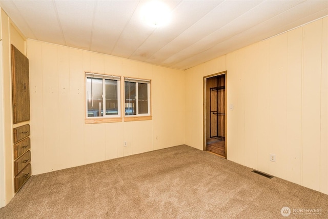 carpeted empty room featuring visible vents