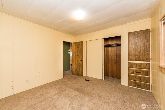 unfurnished bedroom featuring a closet, carpet flooring, visible vents, and elevator