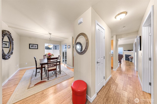 corridor featuring light wood-style flooring and baseboards