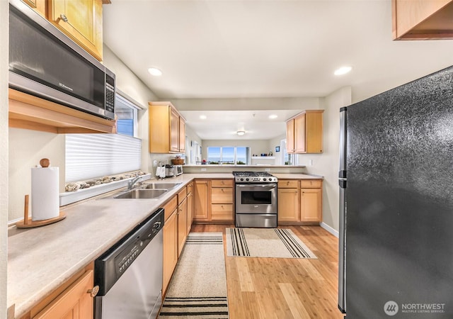 kitchen featuring a sink, appliances with stainless steel finishes, light brown cabinets, and light wood finished floors