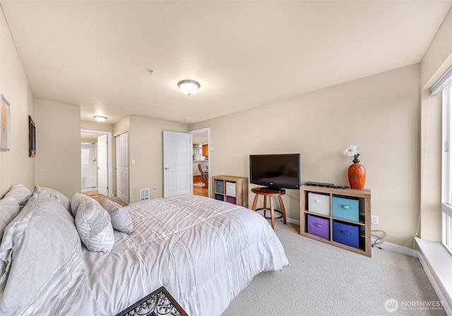 carpeted bedroom featuring a closet, visible vents, connected bathroom, and baseboards