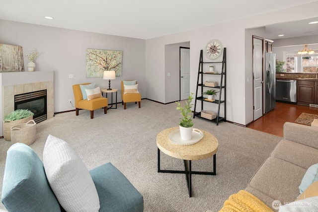 living area featuring baseboards, recessed lighting, a tile fireplace, a notable chandelier, and dark carpet