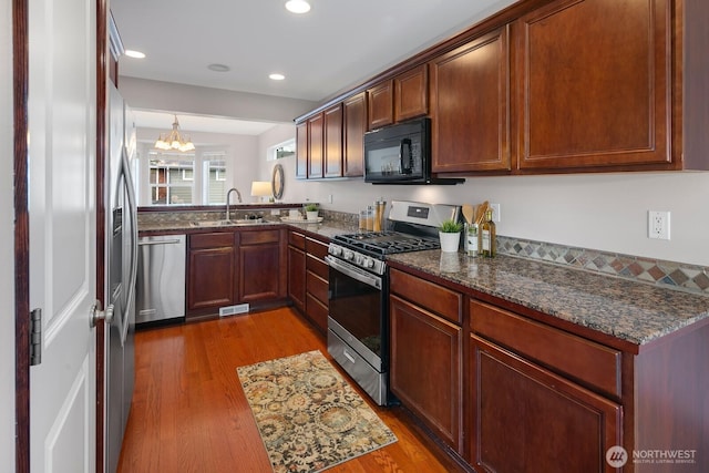 kitchen featuring visible vents, appliances with stainless steel finishes, wood finished floors, and a sink