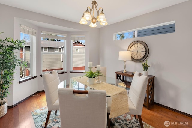 dining space featuring a wealth of natural light, a notable chandelier, baseboards, and wood finished floors