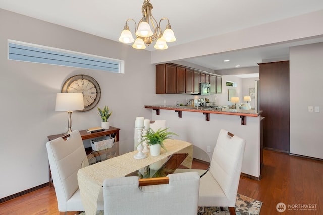 dining area with recessed lighting, baseboards, wood finished floors, and a chandelier