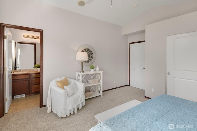 bedroom featuring visible vents, vaulted ceiling, light carpet, ensuite bathroom, and a sink