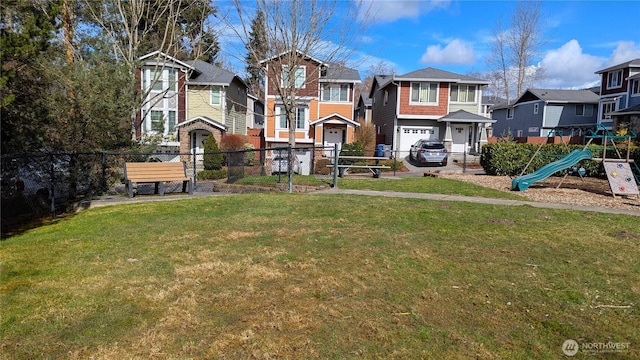 view of yard featuring playground community, a residential view, a garage, and fence