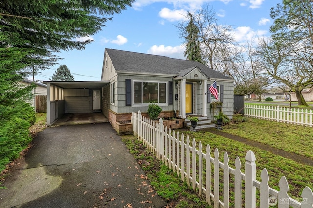 bungalow featuring a fenced front yard, a carport, roof with shingles, and driveway