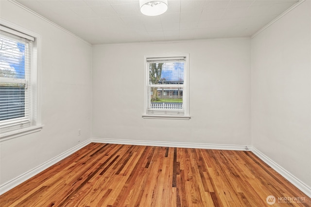 empty room featuring wood finished floors, baseboards, and ornamental molding